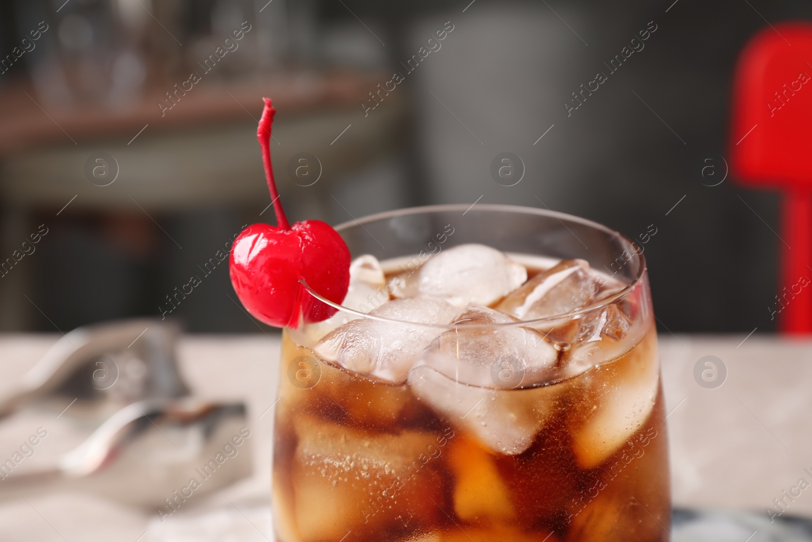 Photo of Tasty cola with ice cubes and cherry in glass, closeup