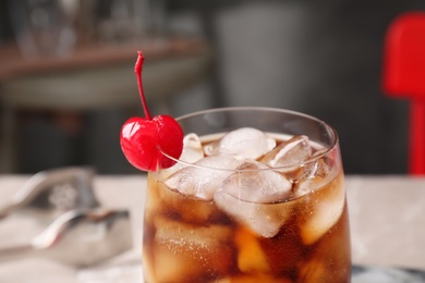 Photo of Tasty cola with ice cubes and cherry in glass, closeup