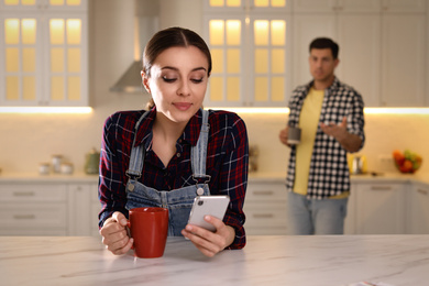 Photo of Woman preferring smartphone over spending time with her boyfriend at home. Jealousy in relationship