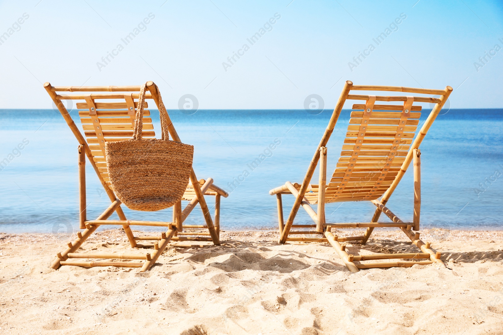 Photo of Wooden deck chairs on sandy beach near sea