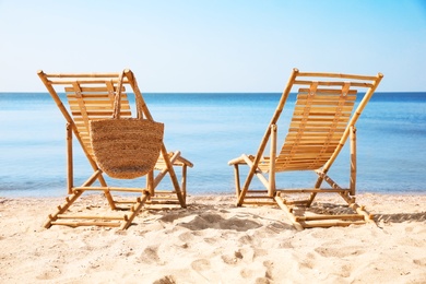 Photo of Wooden deck chairs on sandy beach near sea