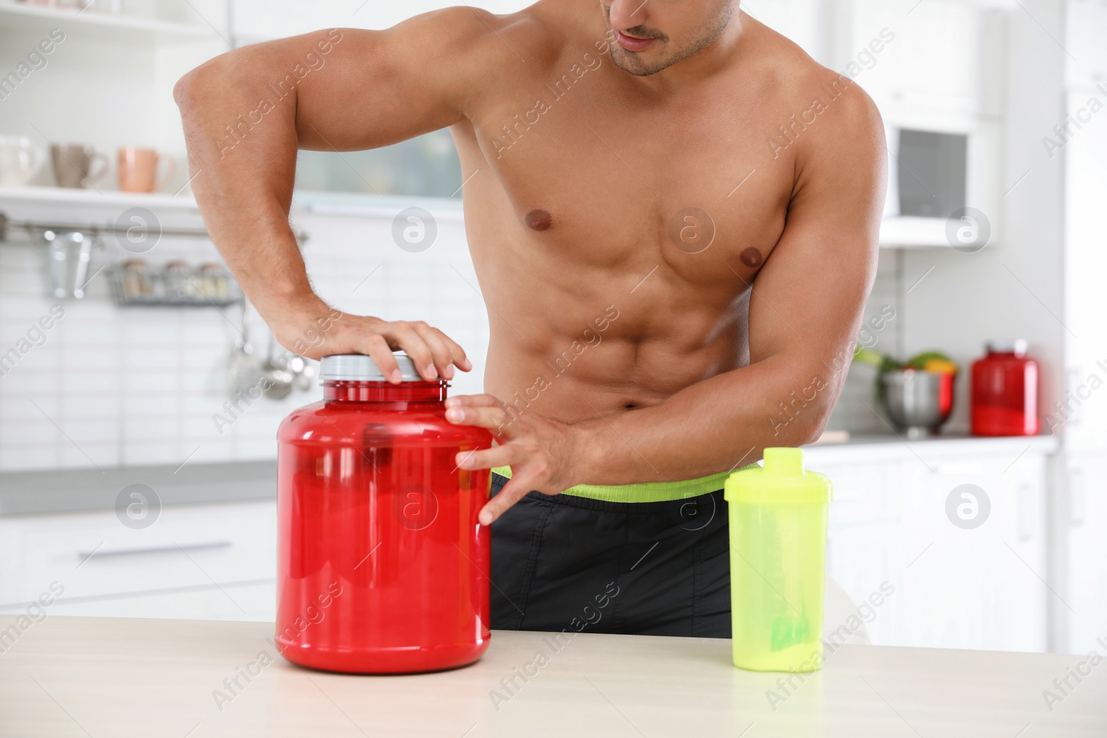 Photo of Young shirtless athletic man preparing protein shake in kitchen, closeup view