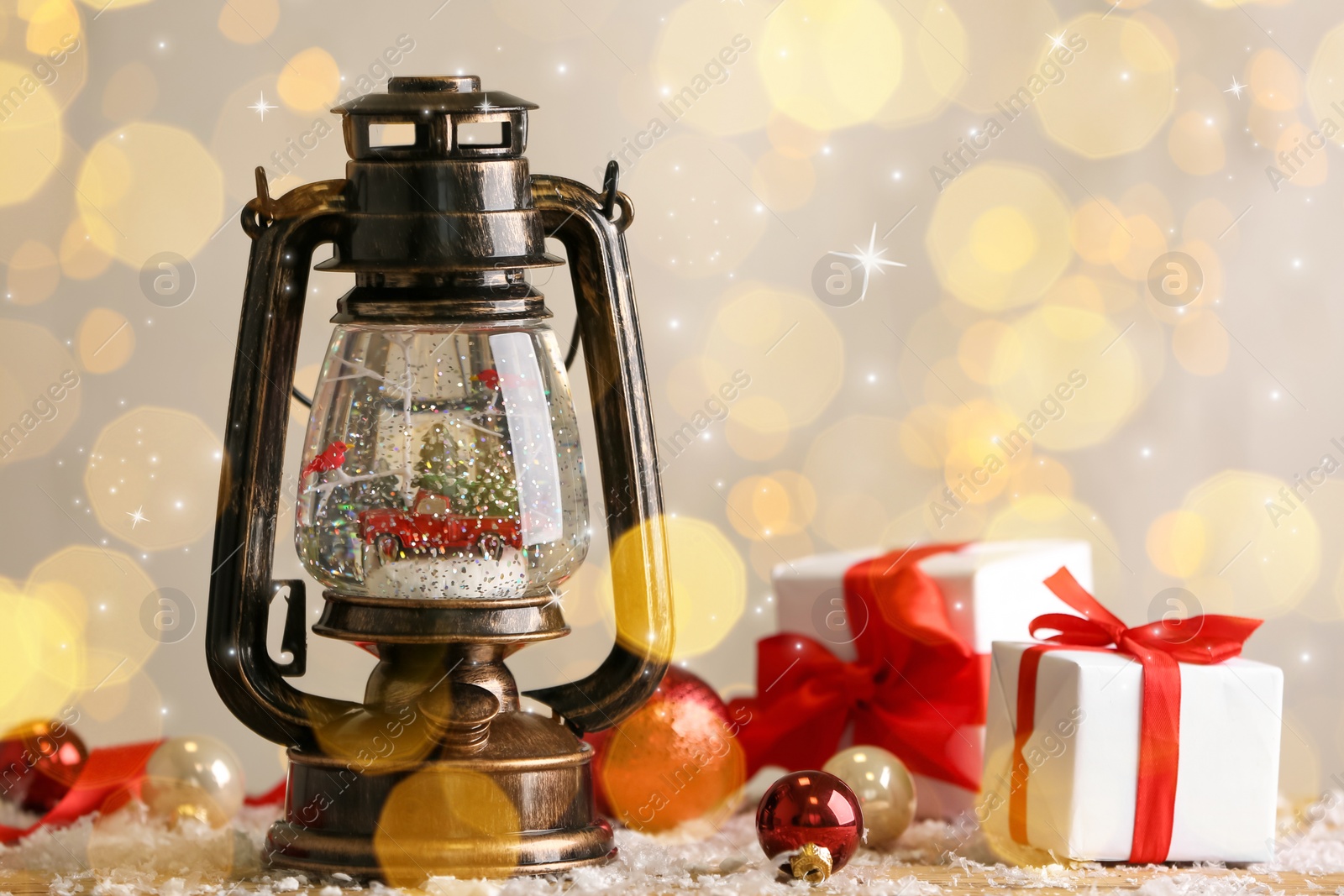 Image of Beautiful snow globe in vintage lantern, gift boxes and Christmas decor on table. Bokeh effect