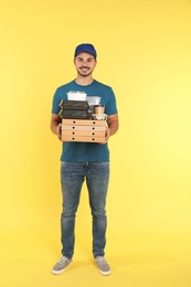 Young courier with different orders on color background. Food delivery service