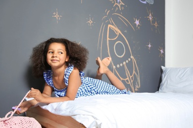 Photo of African-American child lying on bed near chalk drawing of rocket
