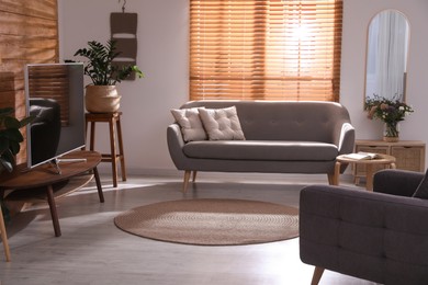 Photo of Stylish living room interior with TV on table and houseplants 