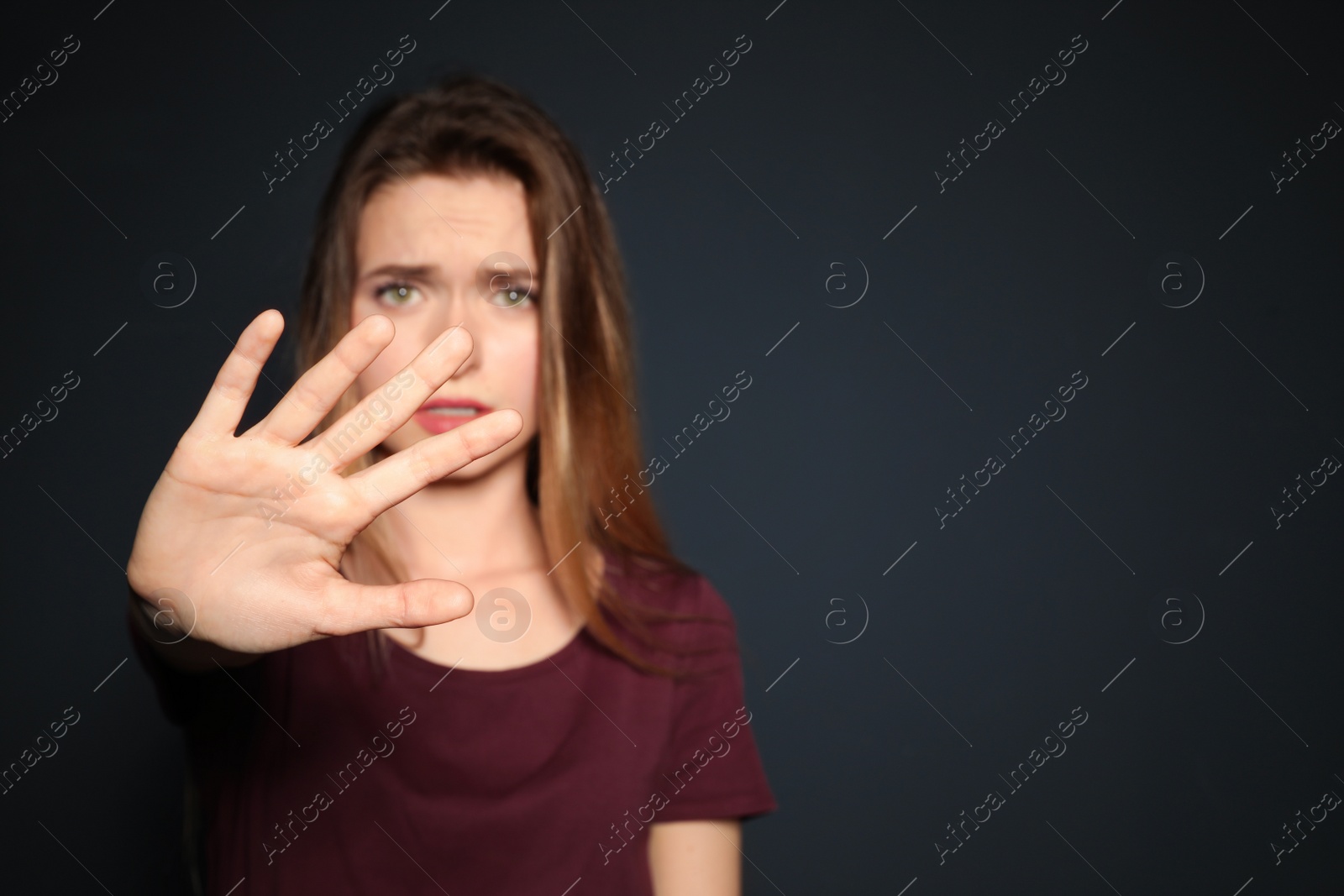 Photo of Young woman making stop gesture against dark background, focus on hand. Space for text