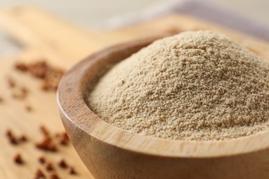 Photo of Bowl of buckwheat flour on wooden board, closeup
