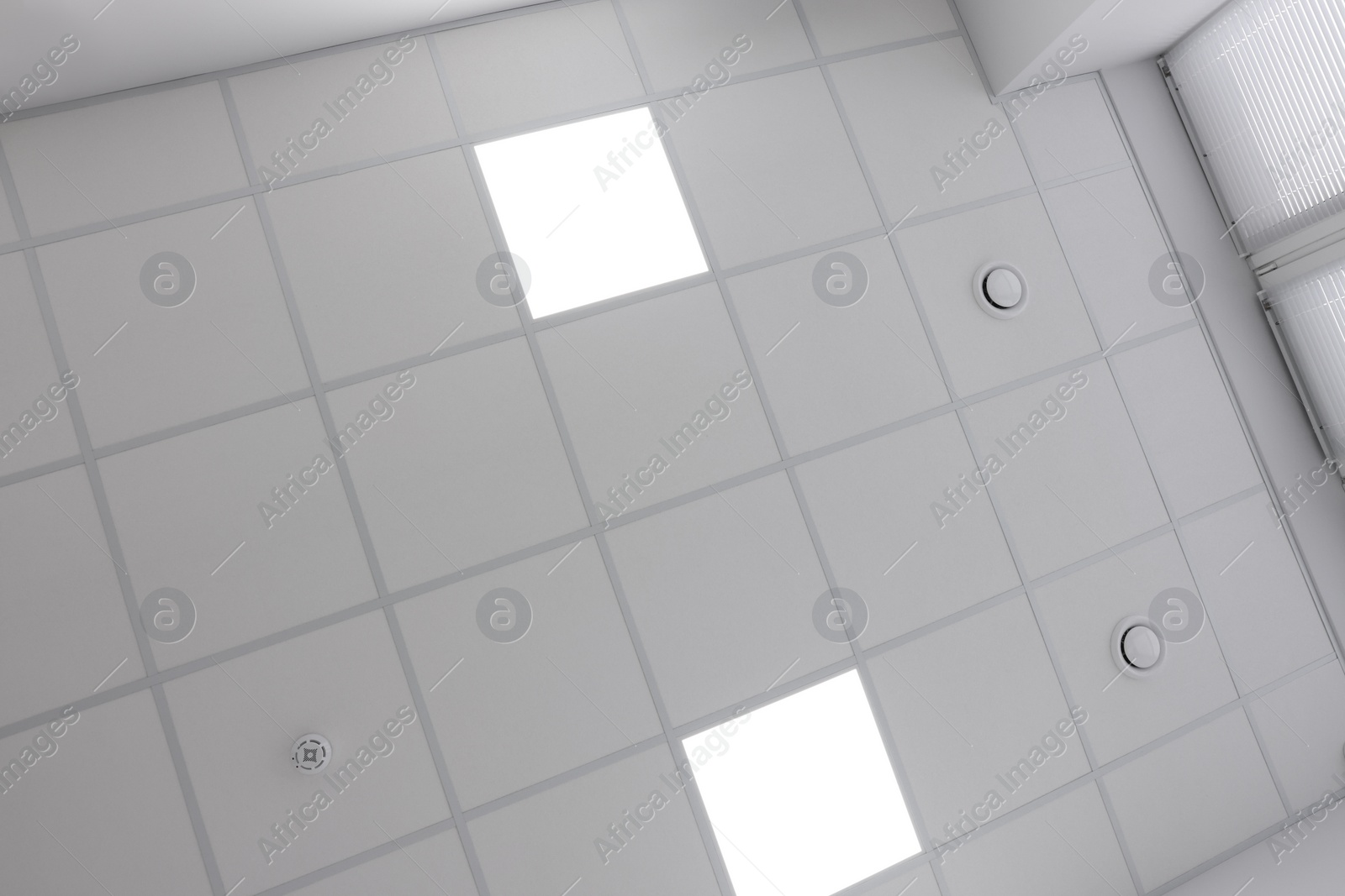 Photo of White ceiling with PVC tiles and lighting indoors, bottom view