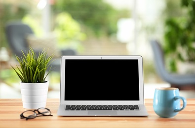 Laptop with blank screen on office table. Mock up for design