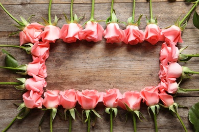 Frame made with beautiful roses on wooden table