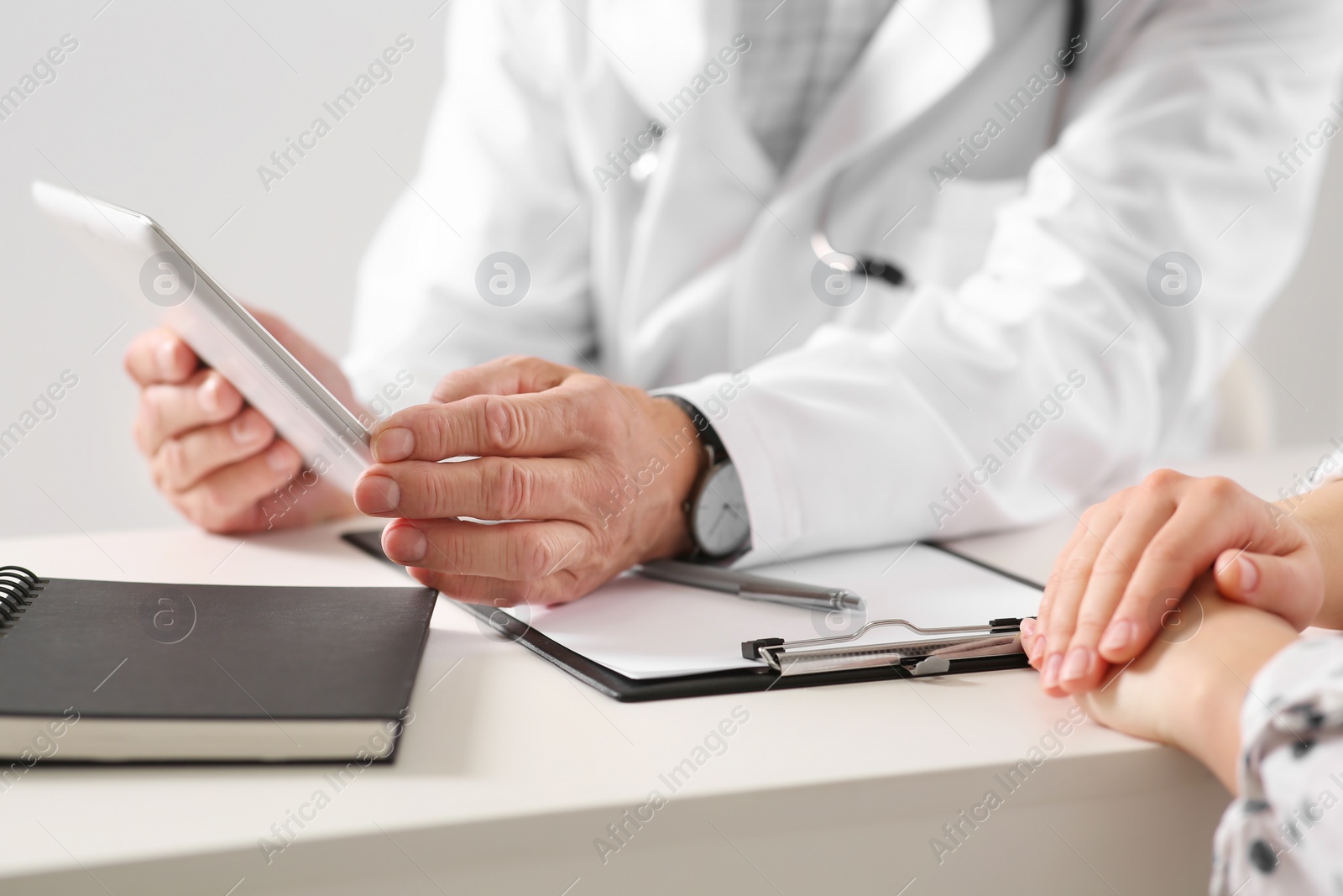 Photo of Patient having appointment with senior doctor at table in clinic, closeup