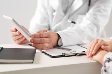 Photo of Patient having appointment with senior doctor at table in clinic, closeup