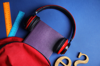 Photo of Flat lay composition with book and headphones on blue background