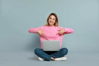 Photo of Young woman with modern laptop on grey background