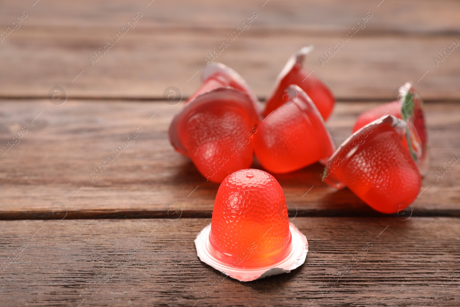 Photo of Tasty bright jelly cups on wooden table, space for text