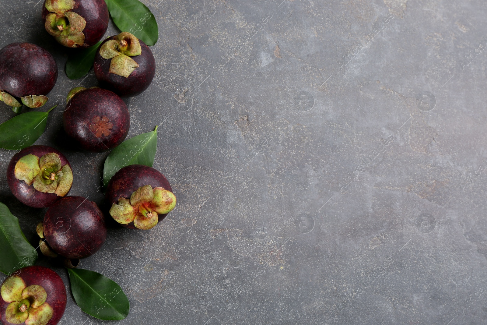 Photo of Fresh ripe mangosteen fruits on grey table, flat lay. Space for text