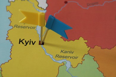 Map of Ukraine with blue and yellow flag push pins placed on Kyiv, closeup