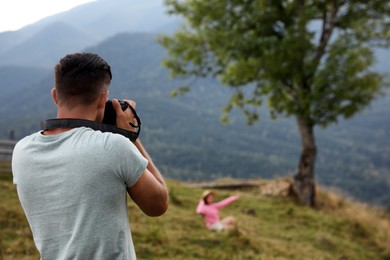 Professional photographer taking picture of woman in mountains, back view