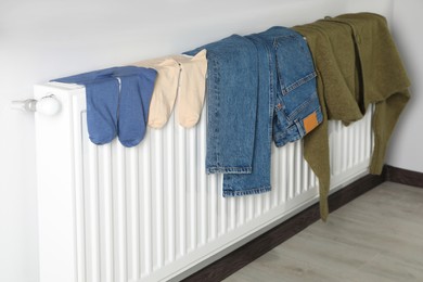Photo of Jeans, socks and cardigan on heating radiator indoors