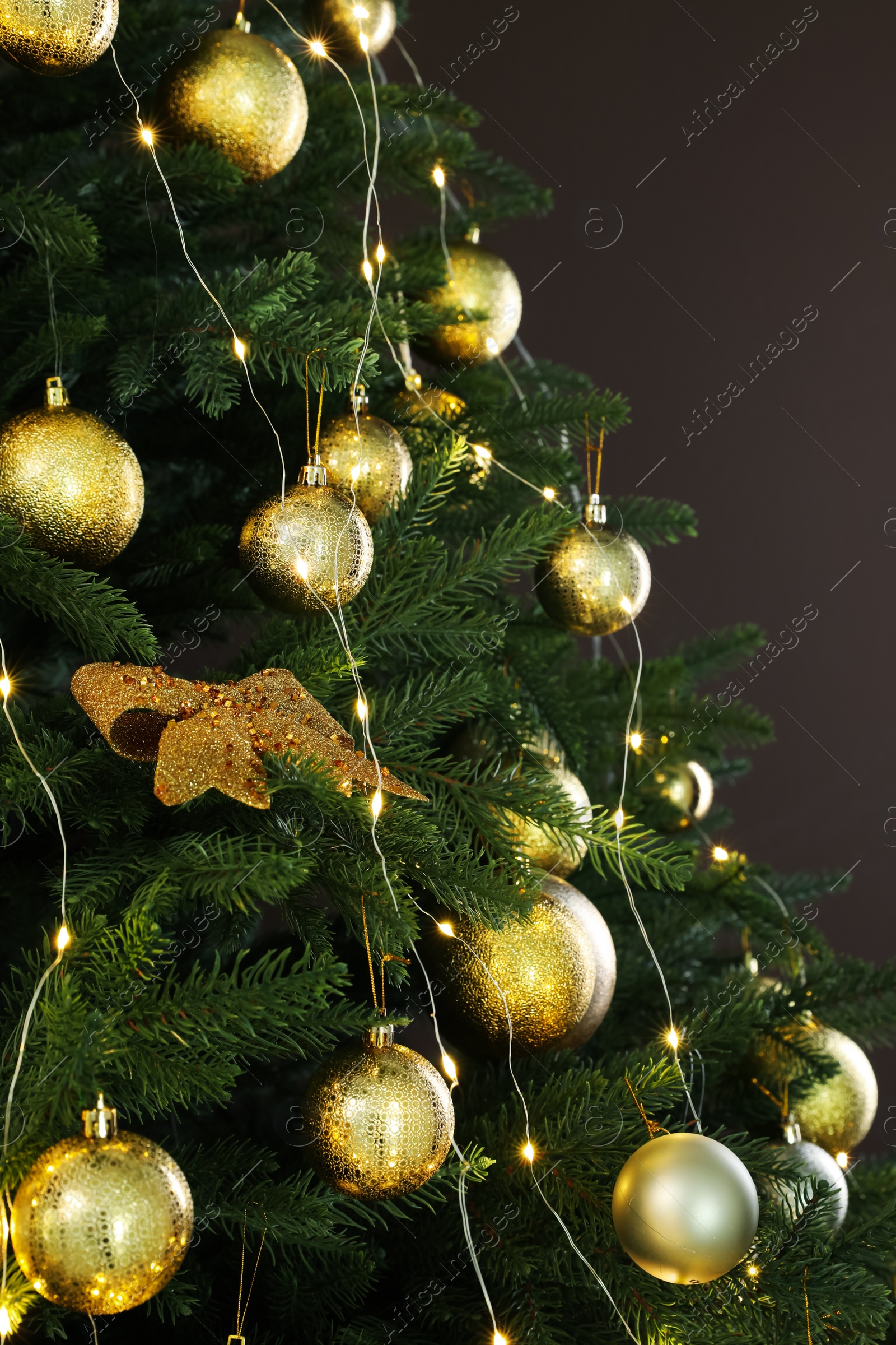 Photo of Beautifully decorated Christmas tree on brown background, closeup