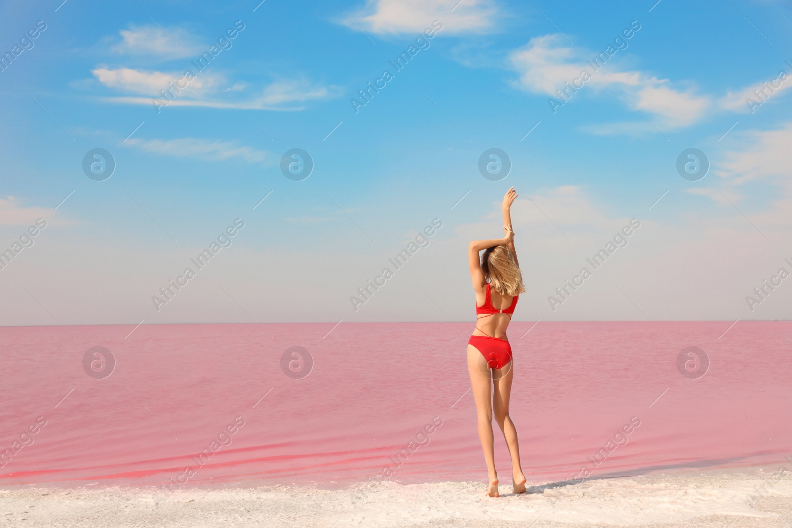 Photo of Beautiful woman in swimsuit posing near pink lake on sunny day