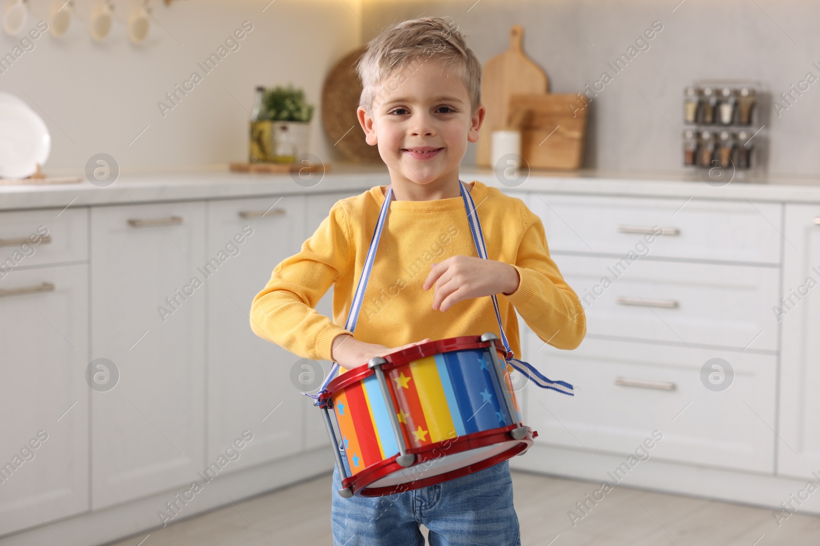 Photo of Little boy playing toy drum in kitchen