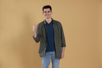 Portrait of happy young man on beige background