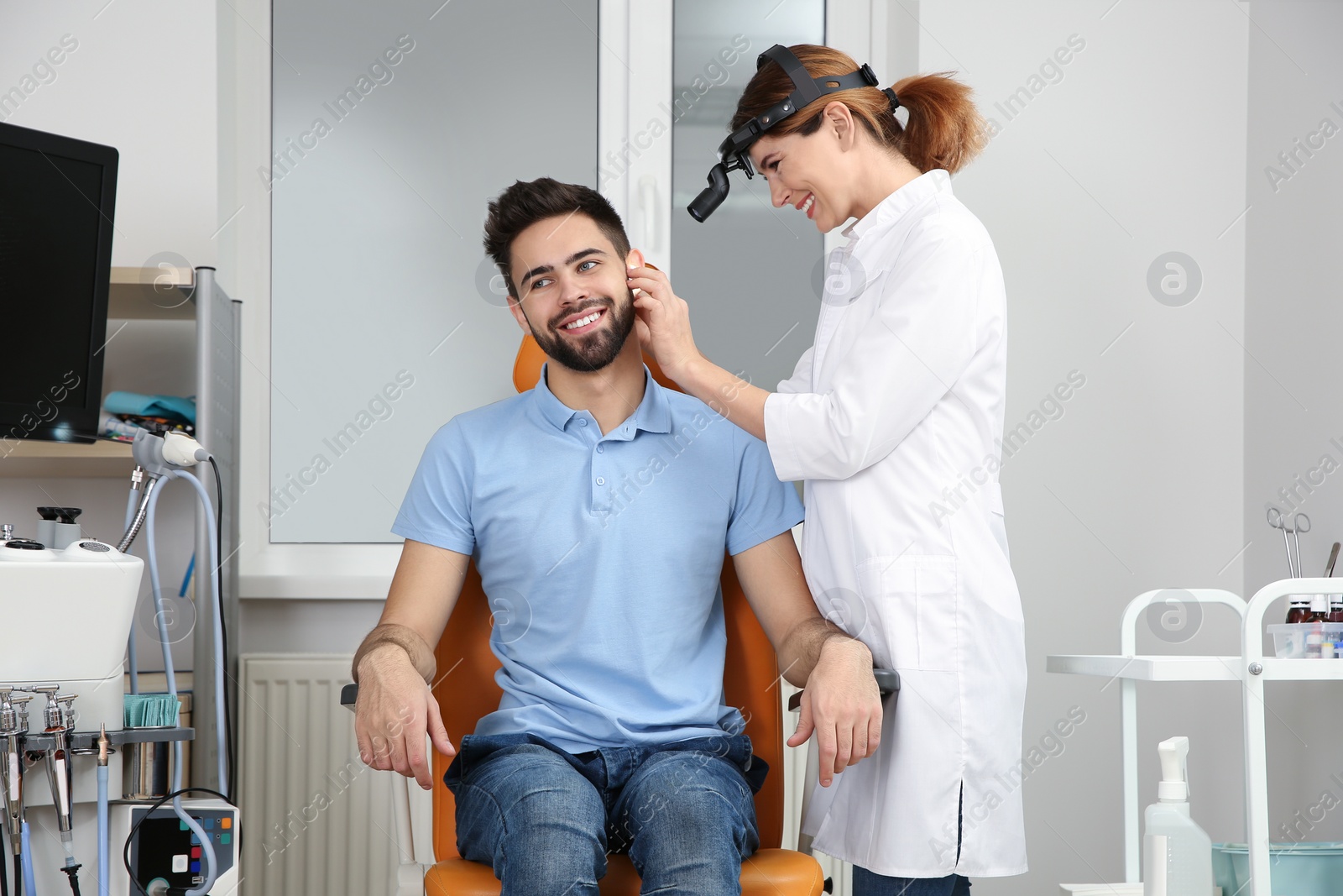 Photo of Professional otolaryngologist examining man in clinic. Hearing disorder
