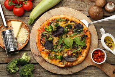 Delicious vegetarian pizza and ingredients on wooden table, flat lay