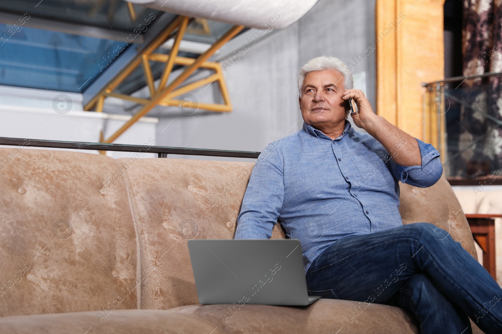 Photo of Senior business owner talking on phone in his restaurant