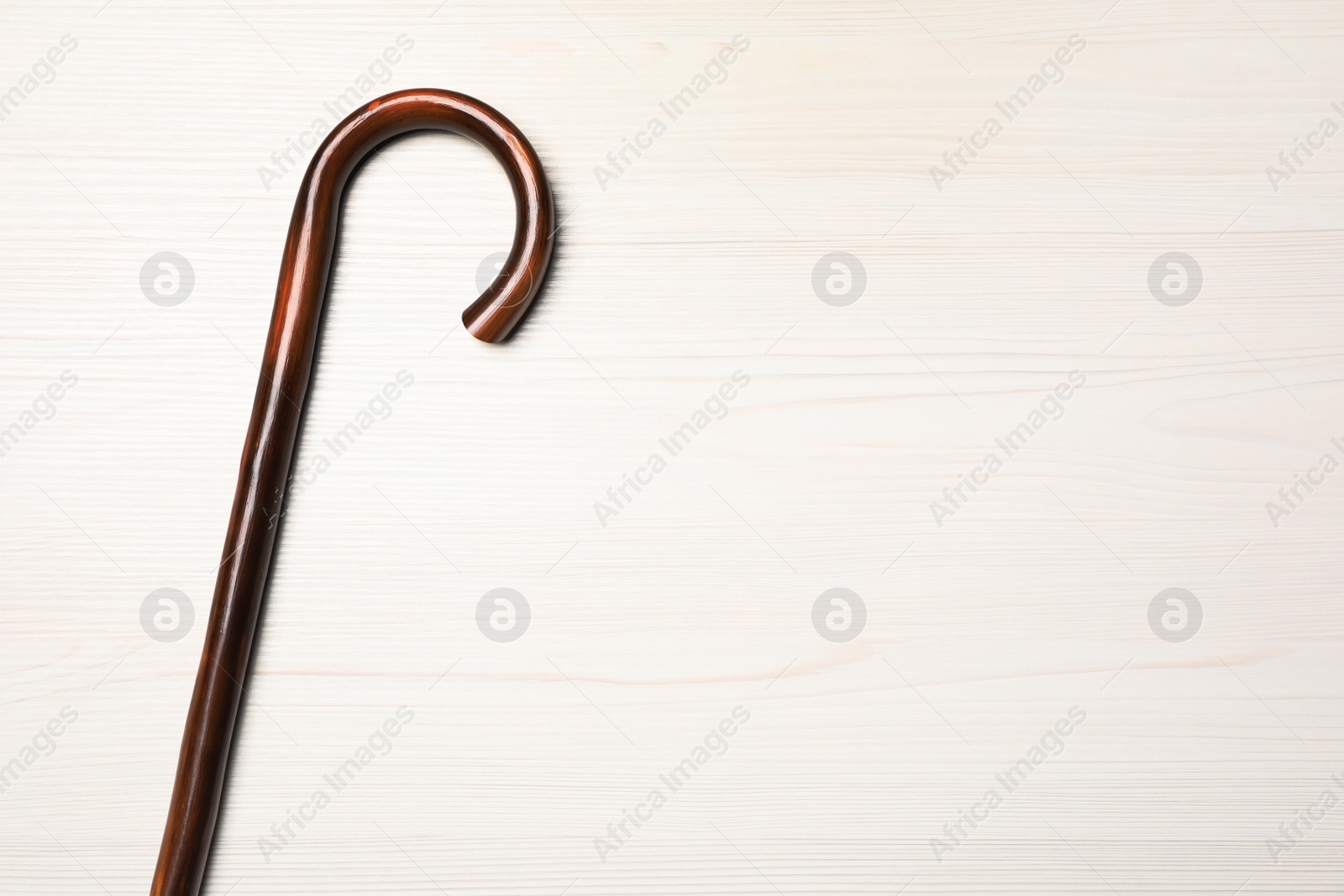 Photo of Walking cane on white wooden background, top view. Space for text