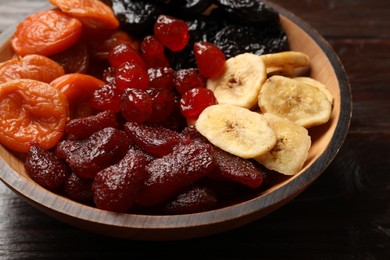 Photo of Mixdelicious dried fruits in bowl on wooden table, closeup