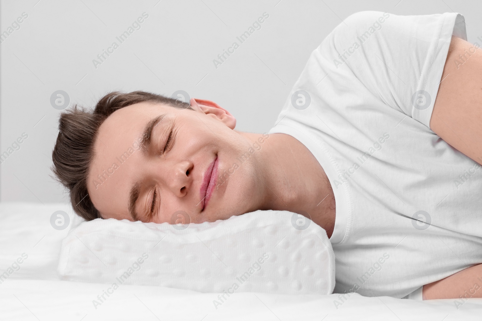 Photo of Man sleeping on orthopedic pillow against light grey background