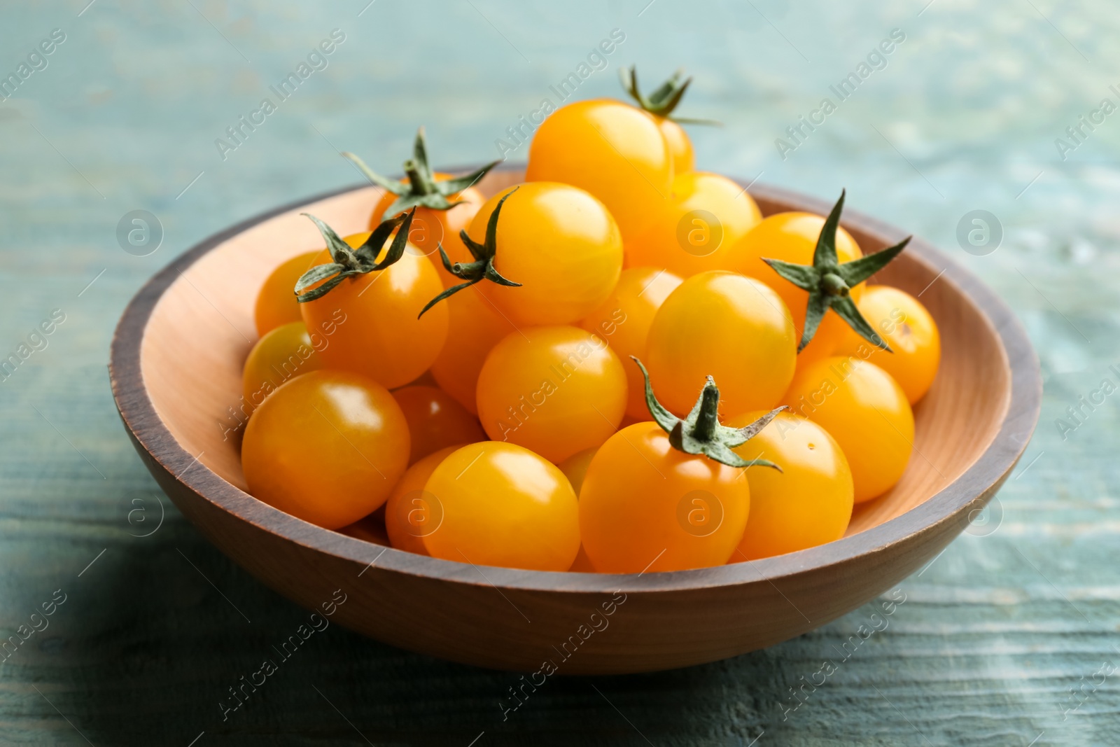 Photo of Ripe yellow tomatoes on light blue wooden table