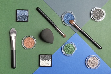 Photo of Flat lay composition with eyeshadows and cosmetic brushes on color background