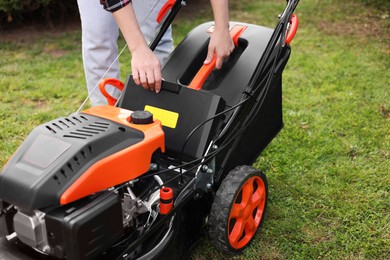 Photo of Woman with modern lawn mower in garden, closeup