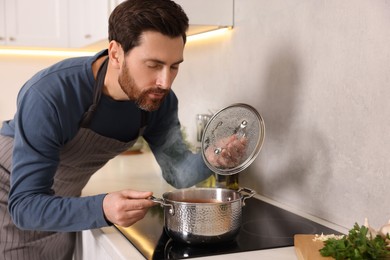 Man cooking delicious tomato soup in kitchen