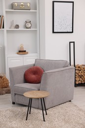 Photo of Comfortable armchair, shelves and coffee table in living room. Interior design