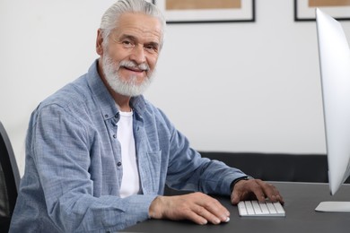 Photo of Handsome senior man working on computer at table in office. Space for text