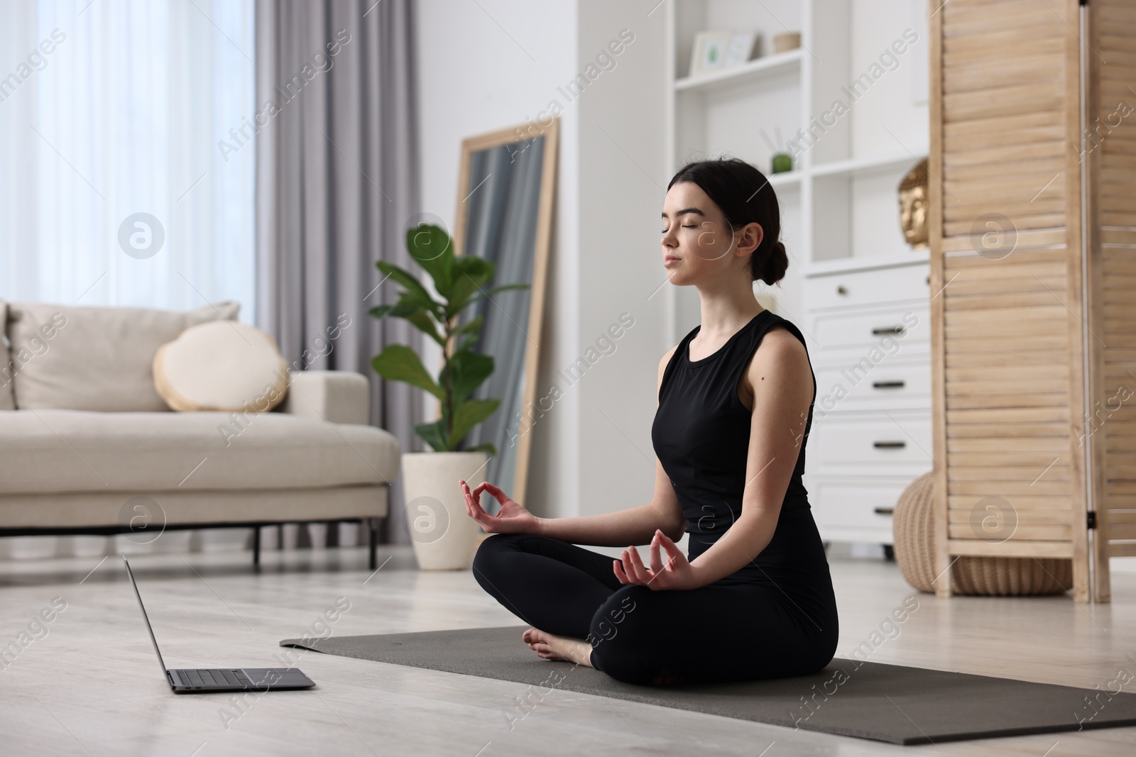 Photo of Beautiful girl having yoga class with online couch at home
