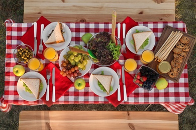 Picnic table with snacks and drink in park, top view