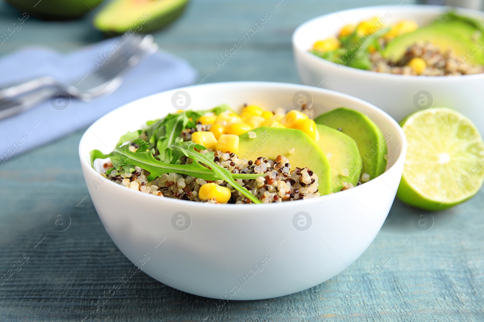 Photo of Healthy quinoa salad with vegetables in bowl on wooden table