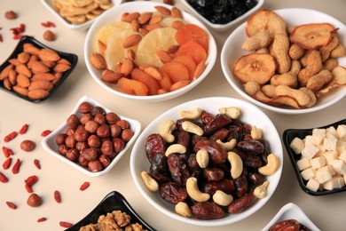 Bowls with dried fruits and nuts on beige background