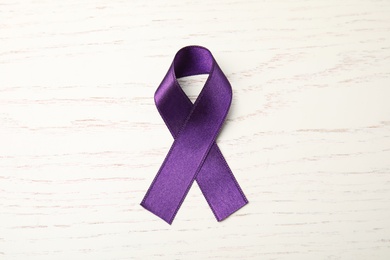 Purple ribbon on white wooden background, top view. Domestic violence awareness