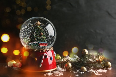 Image of Beautiful snow globe with Christmas tree on dark background, bokeh effect. Space for text