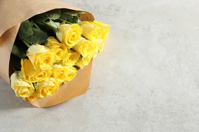 Beautiful bouquet of yellow roses on light grey table, above view. Space for text