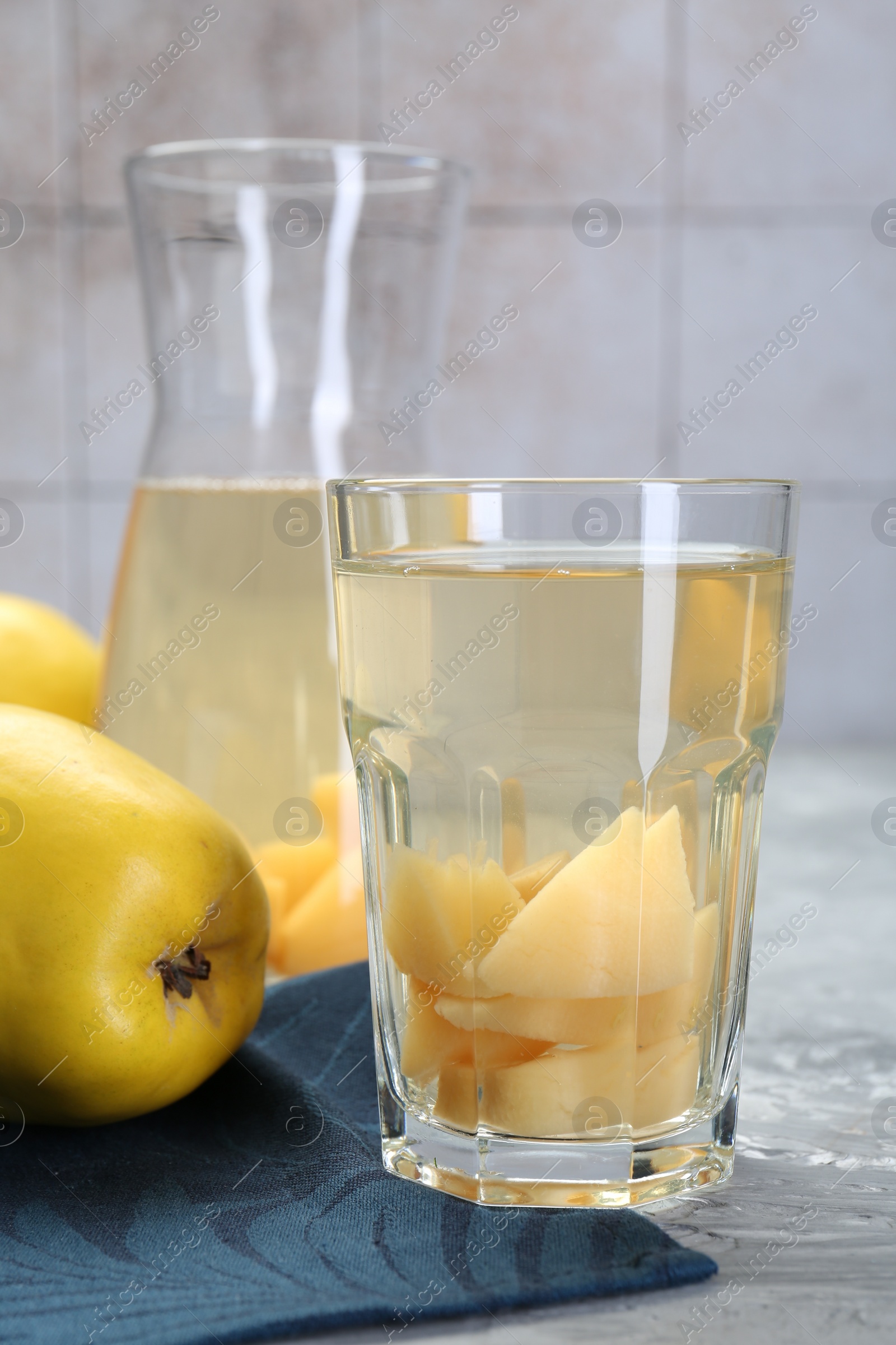 Photo of Delicious quince drink and fresh fruits on grey table