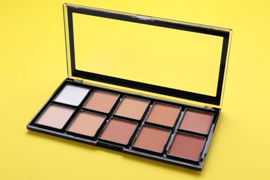 Photo of Colorful contouring palette on yellow background. Professional cosmetic product