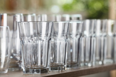 Empty glasses on wooden table against blurred background